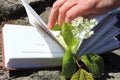 An open book pages a sprig of white cherry blossoms fingers an elderly woman`s wrist