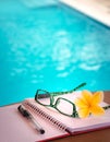 Open Book, Pen and Glasses on The Table Beside Swimming Pool Royalty Free Stock Photo