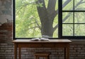 Open book rests on a wooden table in front of a window with a leafy tree outside Royalty Free Stock Photo