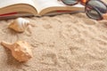 Open book on sandy beach with sea shells and sunglasses, close up lifestyle image Royalty Free Stock Photo