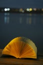 Open book at a sea port at night with a nightlight. Concept: Leasure night reading at the beach Royalty Free Stock Photo