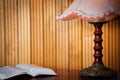 Open book on table and old vintage lamp on wooden background at home in the evening. Horizontal photo. Space for text.