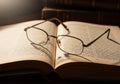 An open book with text visible rests on a surface with eyeglasses Royalty Free Stock Photo