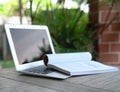 Open book on top of computer laptop. Garden view. Home setting