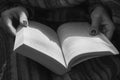 Open book in woman hands, black and white. Girl reading book in park, monochrome. Outdoor relaxation. Reading hobby.