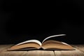 Open book on a wooden table and black background  with copy space for your text Royalty Free Stock Photo