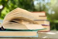 Open book on a wooden table in a garden. Sunny summer day, reading in a vacation concept Royalty Free Stock Photo