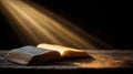 Open book on wooden table illuminated by soft rays of light creating a serene atmosphere Royalty Free Stock Photo