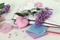 Open books, bookmarks hearts, paper, pencils, branches of lilac flowers on the table