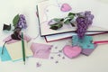 Open books, bookmarks hearts, paper, pencils, branches of lilac flowers on the table