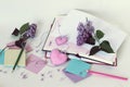 Open books, bookmarks hearts, paper, pencils, branches of lilac flowers on the table