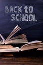 Open books are a stack on the desk, against the background of a chalk board. Difficult homework at school, a mountain of knowledge Royalty Free Stock Photo