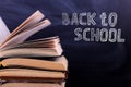 Open books are a stack on the desk, against the background of a chalk board. Difficult homework at school, a mountain of knowledge Royalty Free Stock Photo