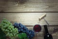 Open bottle of red wine with a glass, corkscrew and ripe grape on a wooden background. Copy space. Royalty Free Stock Photo