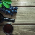 Open bottle of red wine with a glass, corkscrew and ripe grape on a wooden board. Copy space and top view. Royalty Free Stock Photo