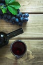 Open bottle of red wine with a glass, corkscrew and ripe grape on a wooden board. Copy space and top view. Royalty Free Stock Photo