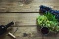 Open bottle of red wine with a glass, corkscrew and ripe grape on a wooden board. Copy space and top view. Royalty Free Stock Photo