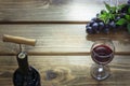 Open bottle of red wine with wineglass, corkscrew and ripe grape on wooden board. Copy space and top view. Royalty Free Stock Photo