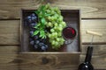 Open bottle of wine with a glass, corkscrew and ripe grape in tray on wooden background. Royalty Free Stock Photo