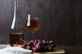 An open bottle of wine next to a glass of pink wine, a bunch of red grapes and a linen table napkin on a wooden board on a wooden Royalty Free Stock Photo