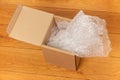 Open box with bubble wrap on a wooden floor Royalty Free Stock Photo