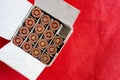Open box of gun cartridges on red background. One cell is empty as a concept of used bullet. Closeup image of ammo