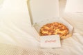 Open box of pizza on the big bed and card with Quote - xo xo xo. Valentine lettering love collection. Concept.