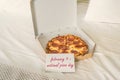 Open box of pizza on the big bed and card with text february 9 - national pizza day. Concept.