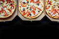 Open boxes with hot tasty italian sliced pizzas on black background Royalty Free Stock Photo