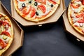 Open boxes with hot tasty italian sliced three pizzas on black background, delicious fast food, delivery concept, top view, copy s