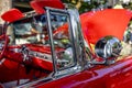 Open bright red vintage retro convertible car with chrome details and moldings exhibited at a provincial town street exhibition