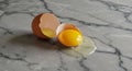 An open brown egg with its shell cracked in half rests on a gray marble countertop. Royalty Free Stock Photo