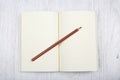 Open brown notebook and a pencil on white wooden table, top view Royalty Free Stock Photo