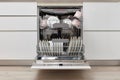 Open built-in dishwasher with clean dishes in white kitchen Royalty Free Stock Photo