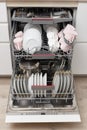 Open built-in dishwasher with clean dishes in white kitchen Royalty Free Stock Photo