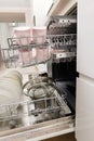 Open built-in dishwasher with clean dishes in white kitchen Royalty Free Stock Photo