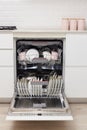 Open built-in dishwasher with clean dishes in white kitchen Royalty Free Stock Photo