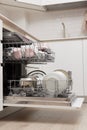 Open built-in dishwasher with clean dishes in white kitchen Royalty Free Stock Photo