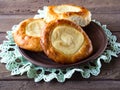 Open buns with cottage cheese vatrushkalying in a clay plate on a wooden table and openwork napkin. ÃÂ¡loseup.