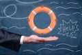 An open businessman`s palm holding an orange life buoy on a blackboard background with chalk drawings. Royalty Free Stock Photo