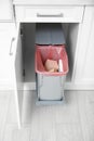 Open cabinet with full trash bin in kitchen Royalty Free Stock Photo