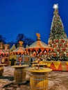 An open cafe at the Christmas Fair on Manezhnaya Square in St. Petersburg, tables from barrels, on them a large Christmas tree, a