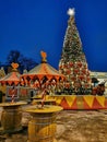 An open cafe at the Christmas Fair on Manezhnaya Square in St. Petersburg, tables from barrels, on them a large Christmas tree, a