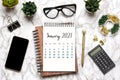 Open Calendar 2021, glasses, cup of coffee, pen, smartphone, succulents on marble table Royalty Free Stock Photo