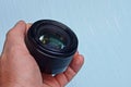 Open camera lens in a hand on a blue background