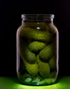 Open can of pickles on a black background and on a green table background