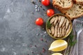 Open can of spicy smoked sprats in oil on a concrete background with peppercorn, lemon, bread, fresh tomatoes. Royalty Free Stock Photo