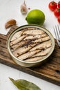 Open can of tinned sardines, Sprats fish, on white stone table background