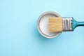 Open can with white paint and brush on blue background, top view Royalty Free Stock Photo