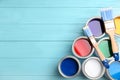 Open cans with paint and brushes on blue wooden table, flat lay